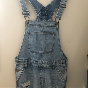Lighter wash denim short overalls.